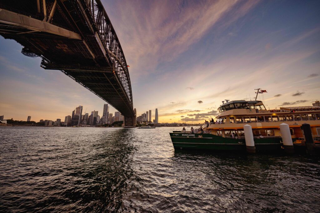 A bridge crossing a body of water at sunset in Sydney, Australia.